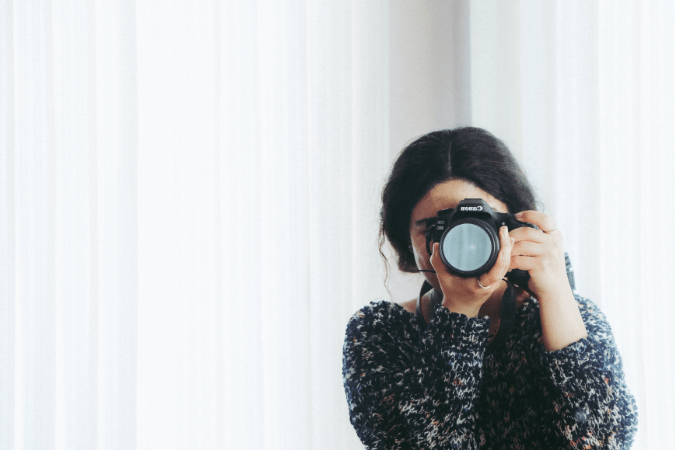 Girl in sweater taking a photo with a professional camera.