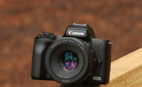 Canon EOS camera sitting on wood board.