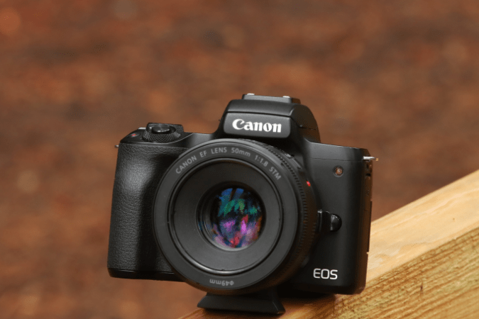 Canon EOS camera sitting on wood board.
